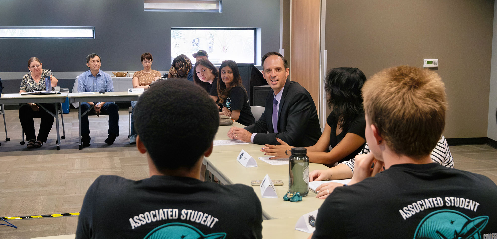 Chancellor Smith and 10 students sit around a u shaped table for a discussion