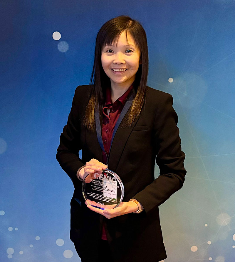 Areeluck Parnsoonthorn stands in front of a bright blue background and holds her award