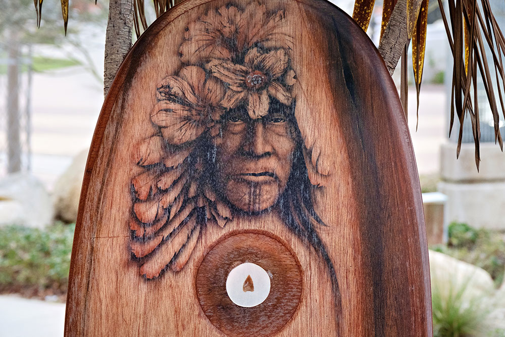 A wooden board with a man's face carved into the top.