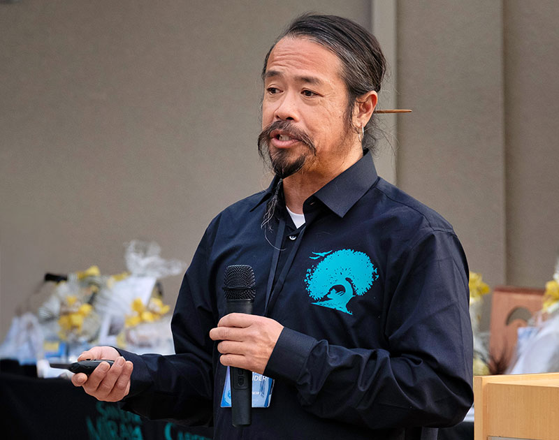 Anh Pham speaks into a microphone during a presentation at Miramar College.