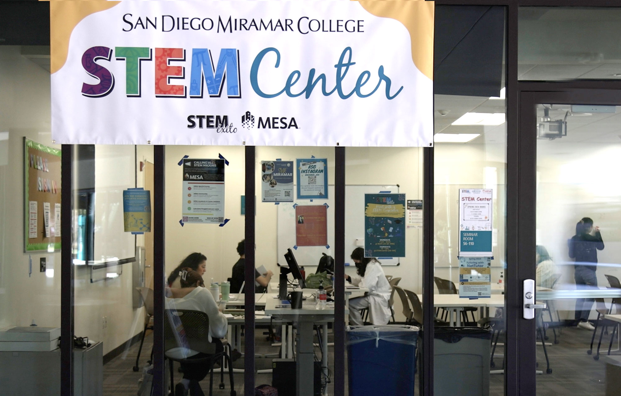 At large Stem banner hangs in front of the glass panels at the entrance of the tutoring center
