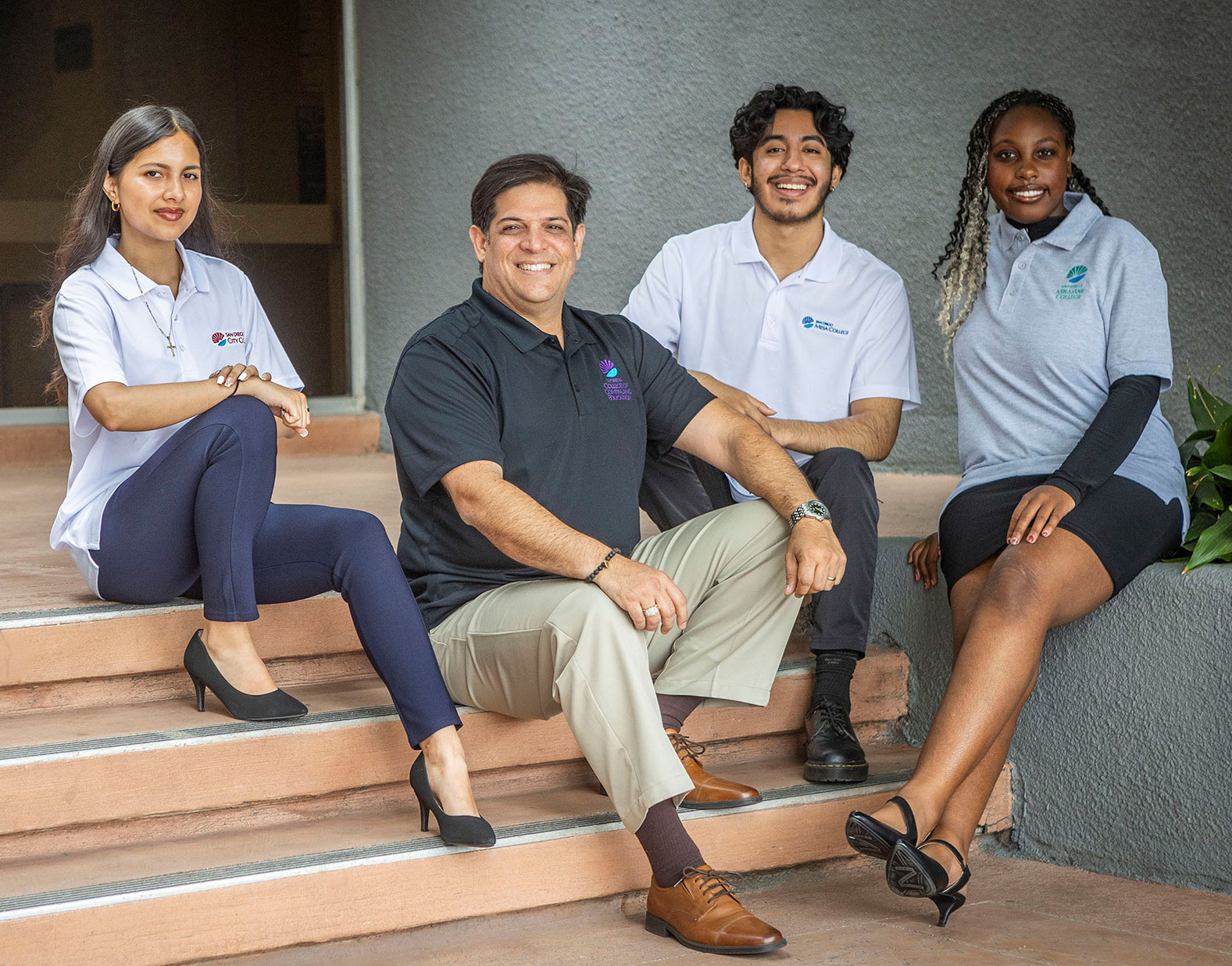 Four student trustees seated on the steps outside of the District Office