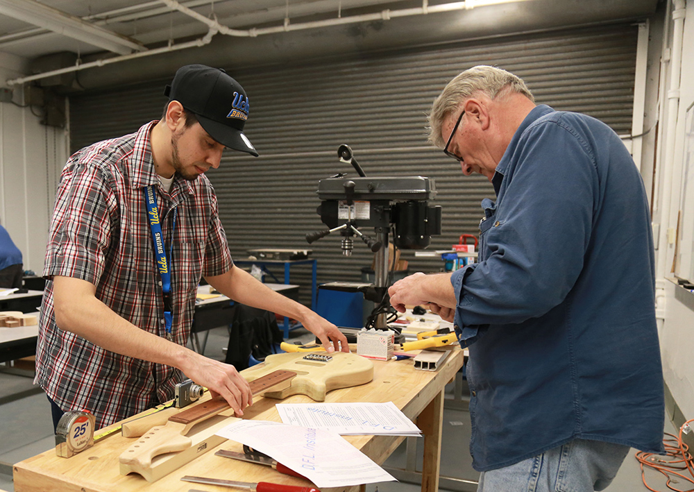 Two students work together in a guitar-building course