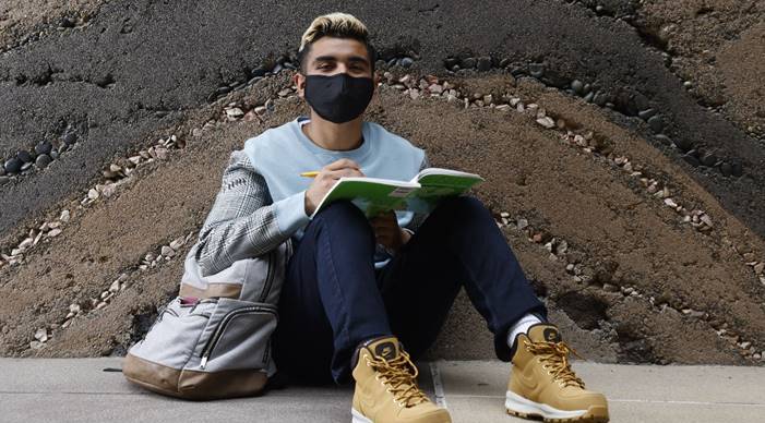 A student studies on campus while wearing a facemask