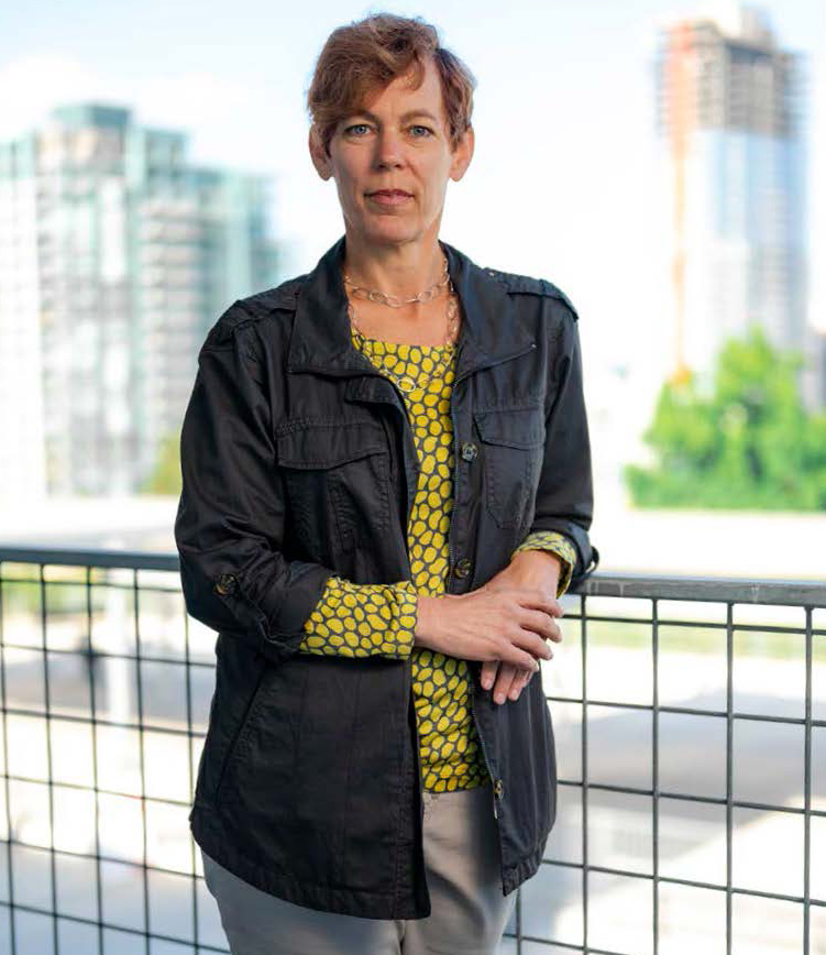 Anna Rogers stands on a balcony with a view of City College in the background