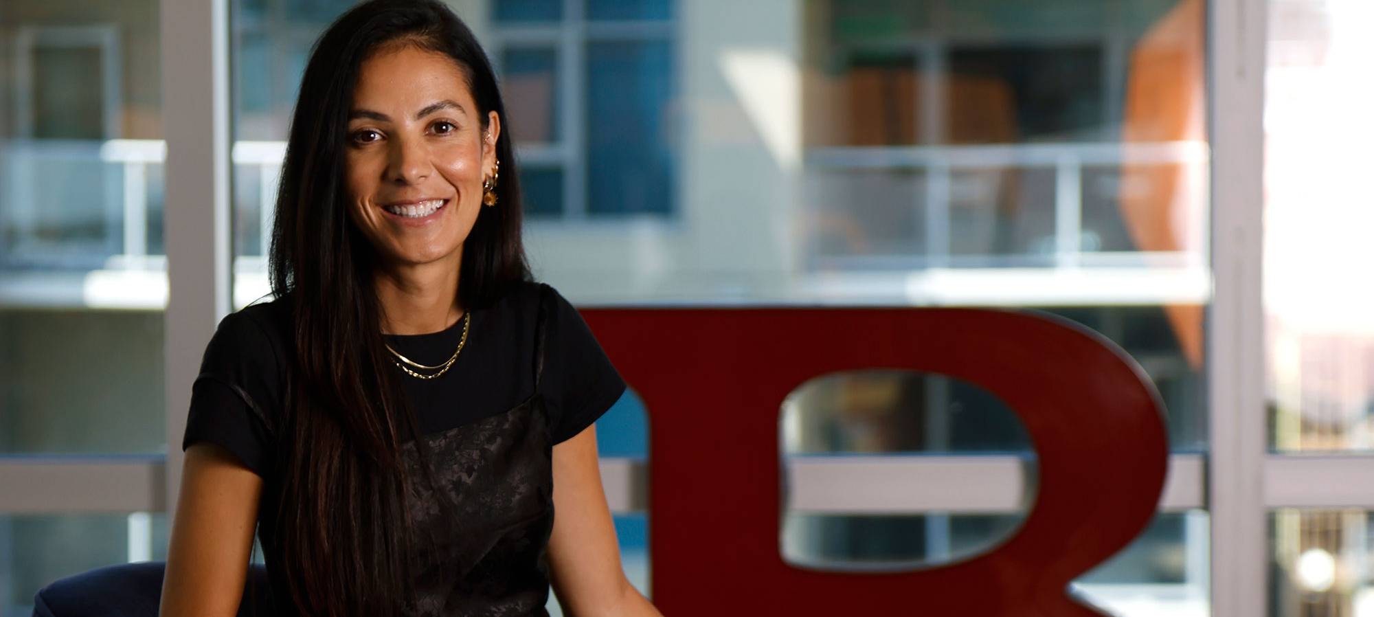 Mayra Favela sitting in a chair and wearing a black dress at her office.