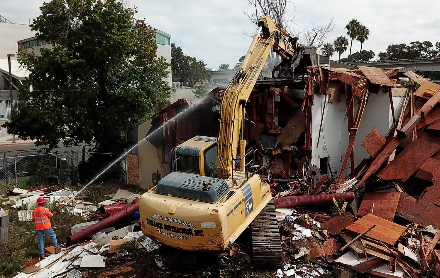 A demolition crew with an earth mover tears down an old building to make room for student housing.