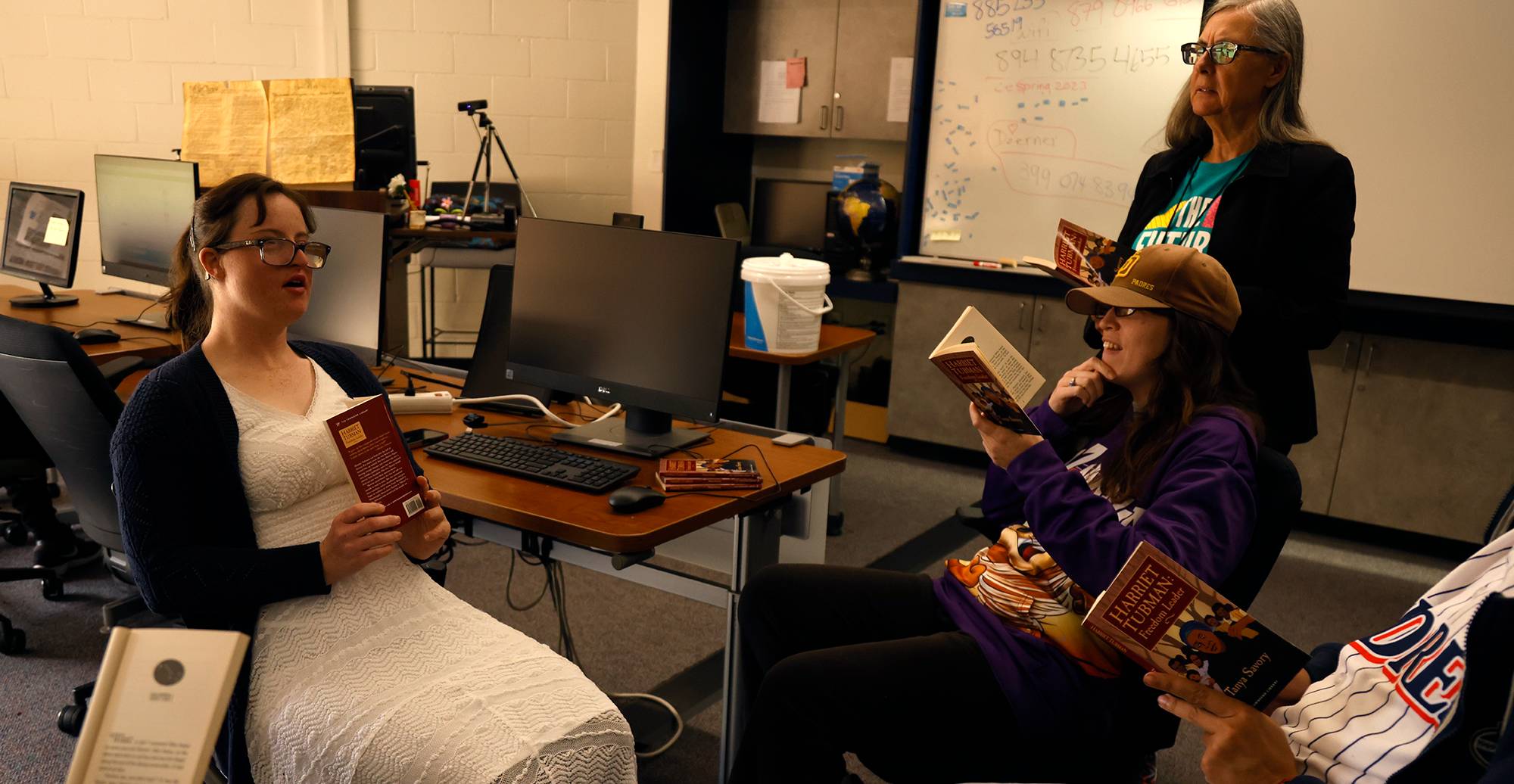 Natalie Jackson participates in a book discussion with her peers while instructor Marie Doerner, standing, watches on.