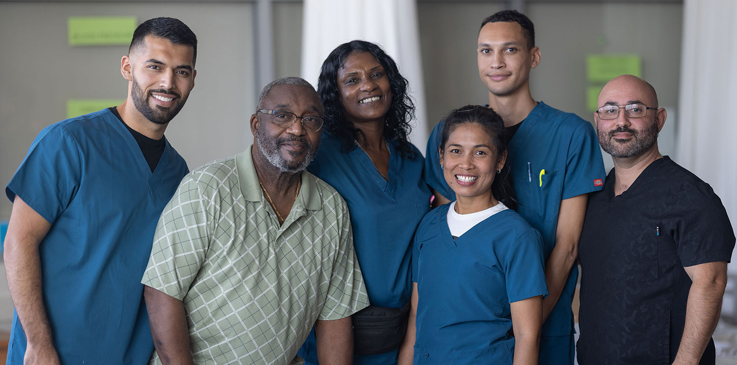 6 people wearing hospital scrubs take a group photo