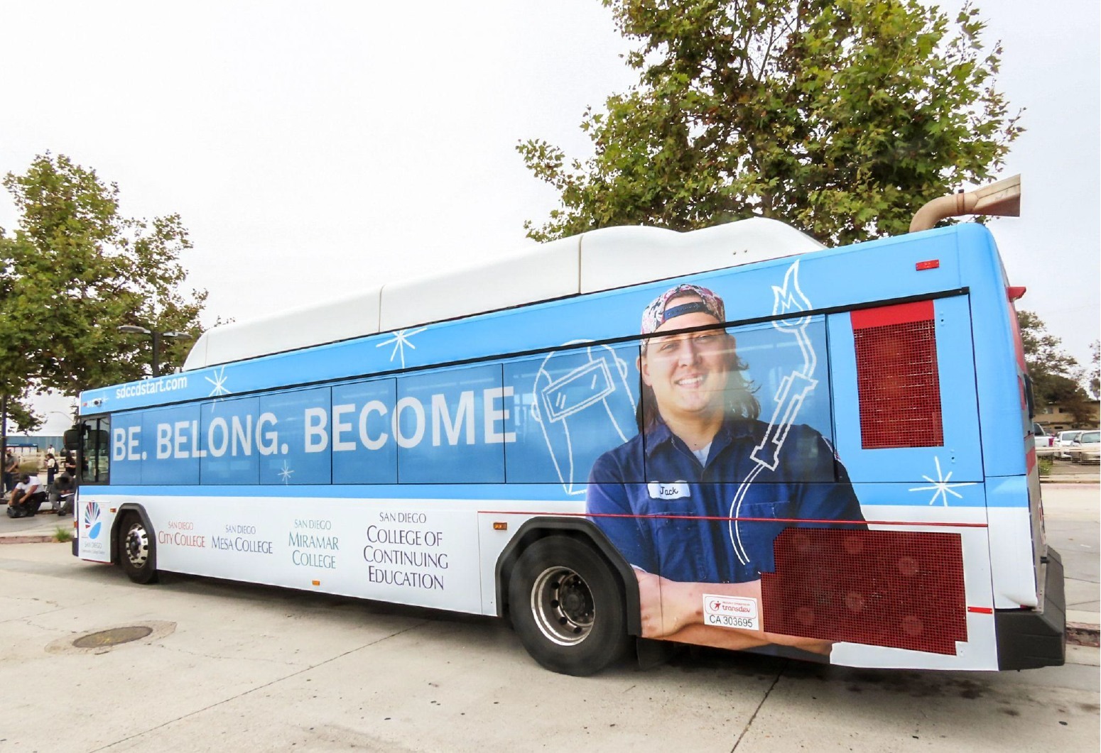 A student and the new tagline be belong become on the side of a bus wrapped in an ad
