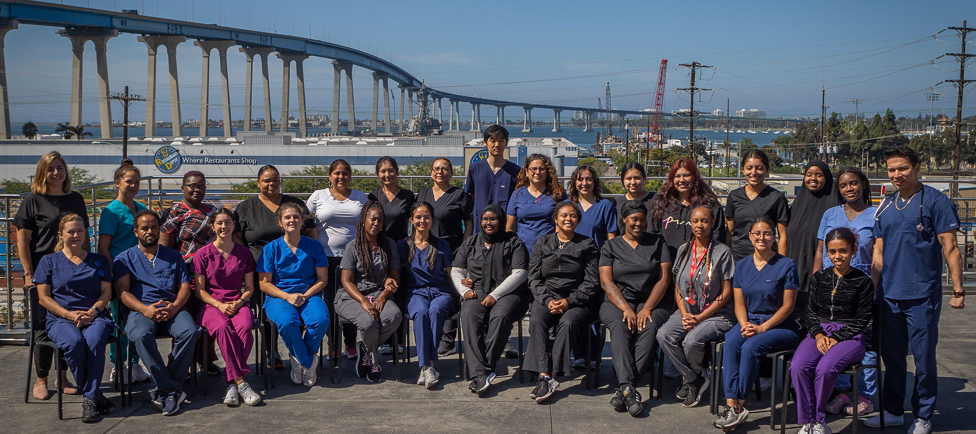 The graduating cna class takes a group photo with the Coronado Bridge in the background