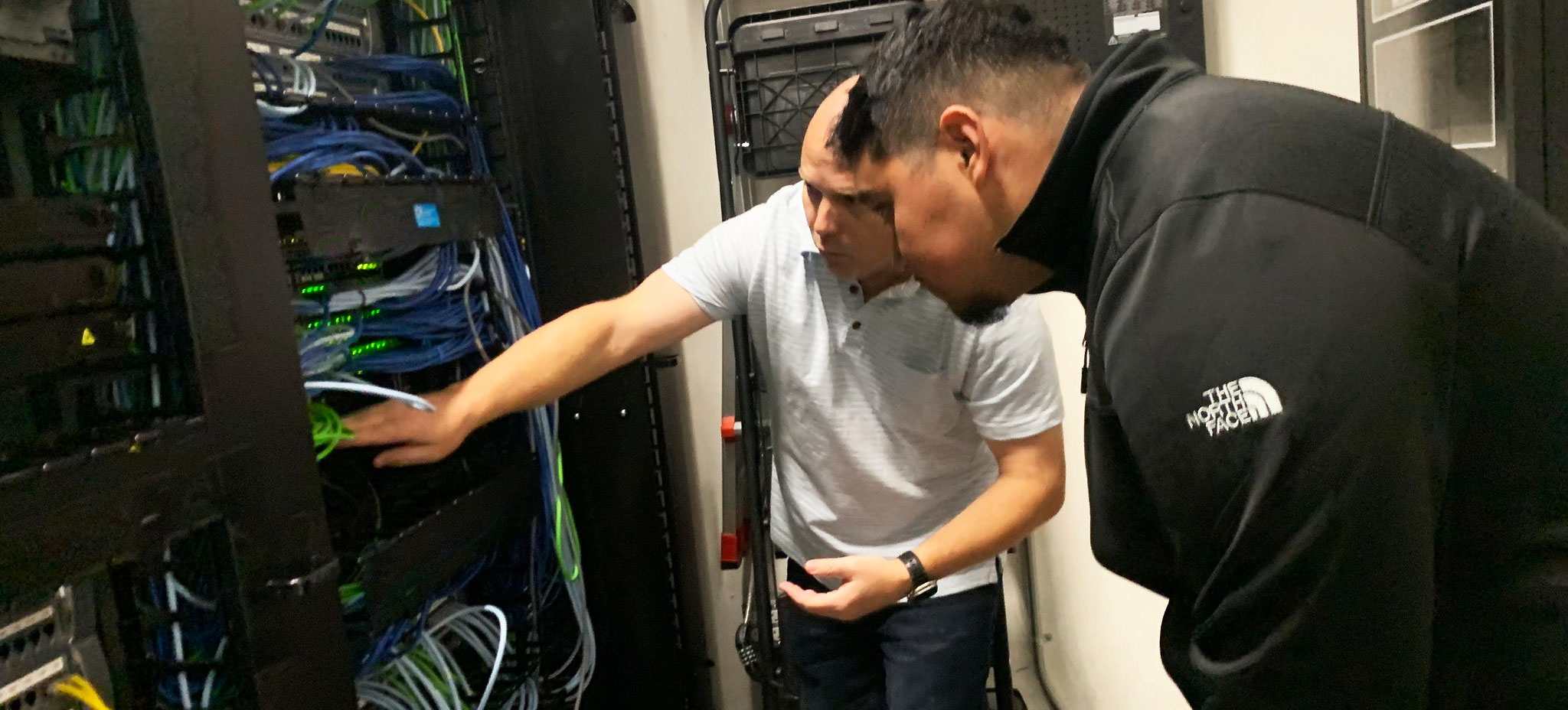 Program director David Kennemer shows a student the wiring of a server at the cyber technology lab