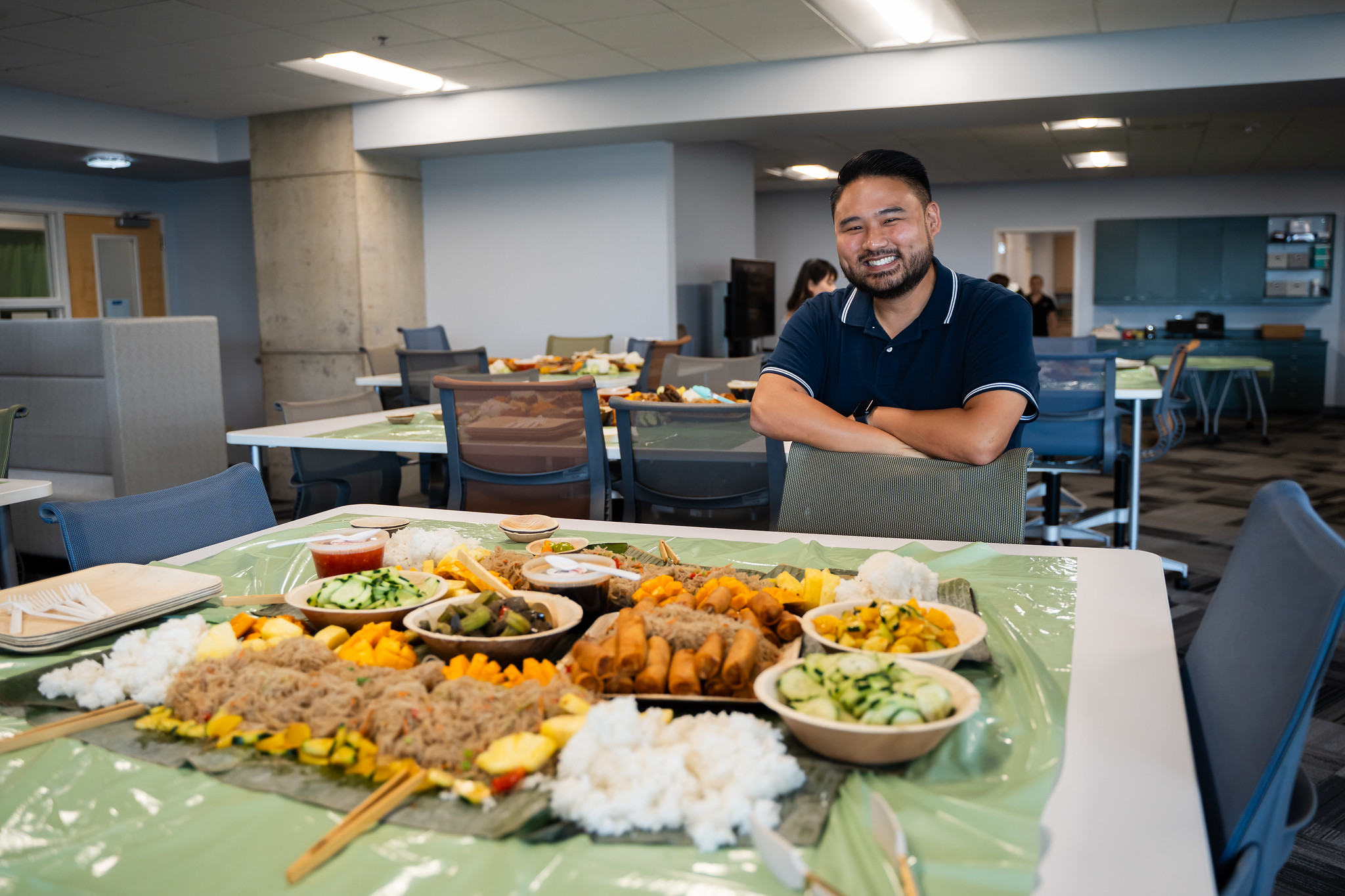 A man stands next to a table full of traditional Filipino food