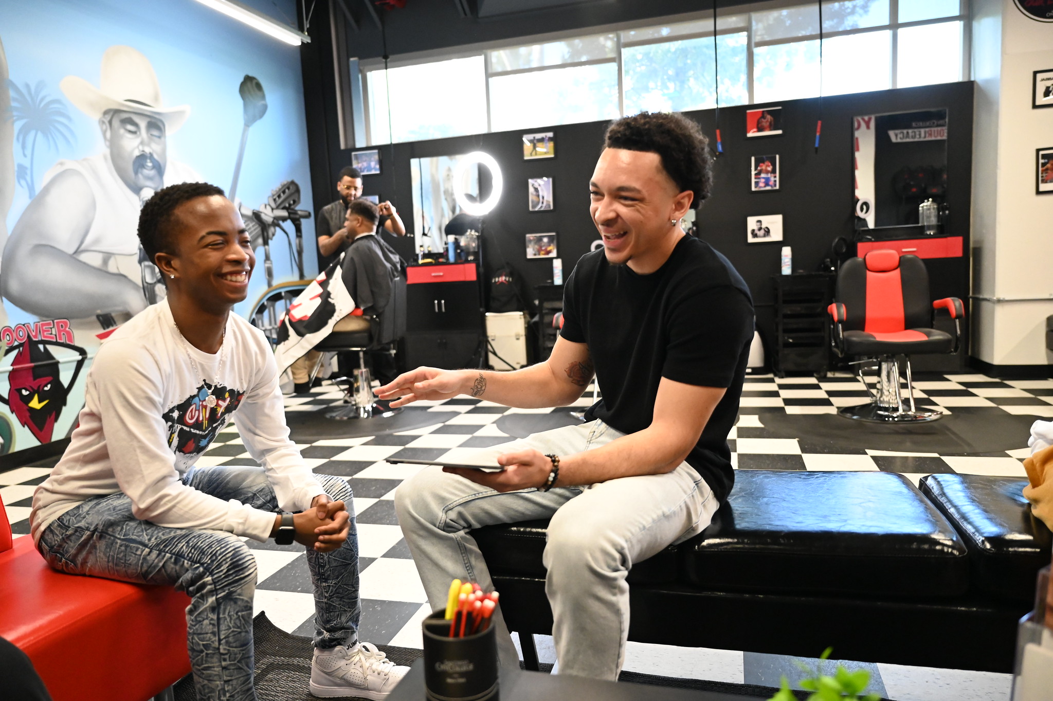 Two men laugh while hanging out at Fresh Cutz barbershop