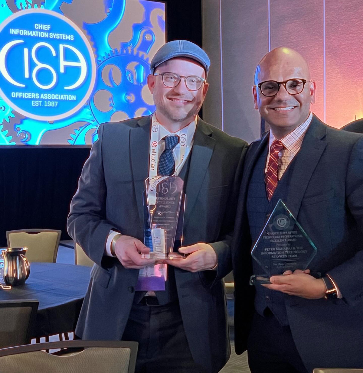 Two men holding glass awards at the award ceremony