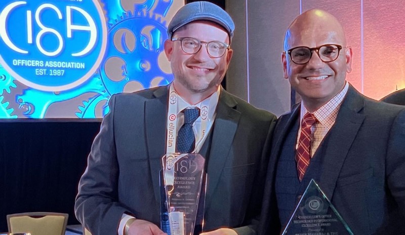 Two employees hold up glass IT award