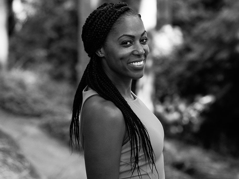 Jessica Walton in a black and white photo is outside among trees.