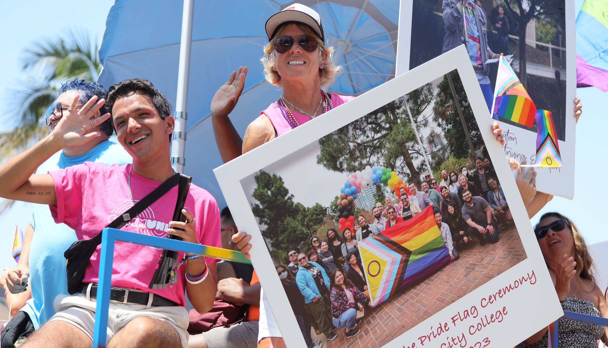 Lisa Carulli on the Pride Parade float holding a large cardboard image of the raising of the pride flag at city college