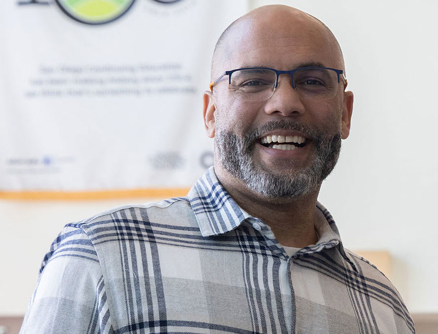 Dr. Terry Siver is smiling and wearing glasses and a blue and white flannel shirt