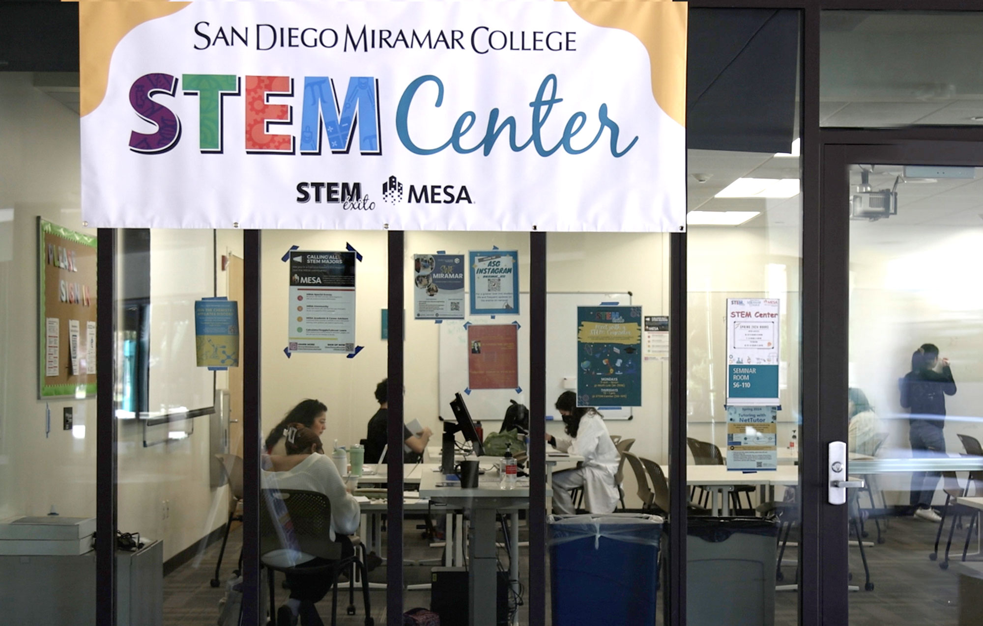 At large Stem banner hangs in front of the glass panels at the entrance of the tutoring center