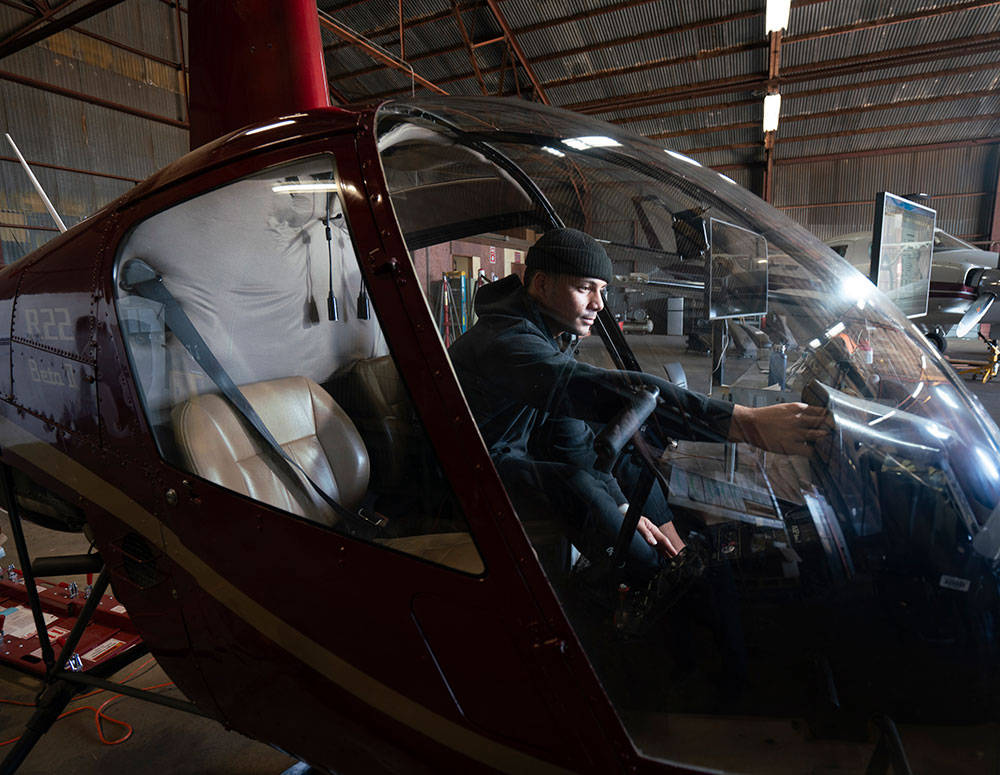 A student reaches for the controls in the cockpit of a helicopter
