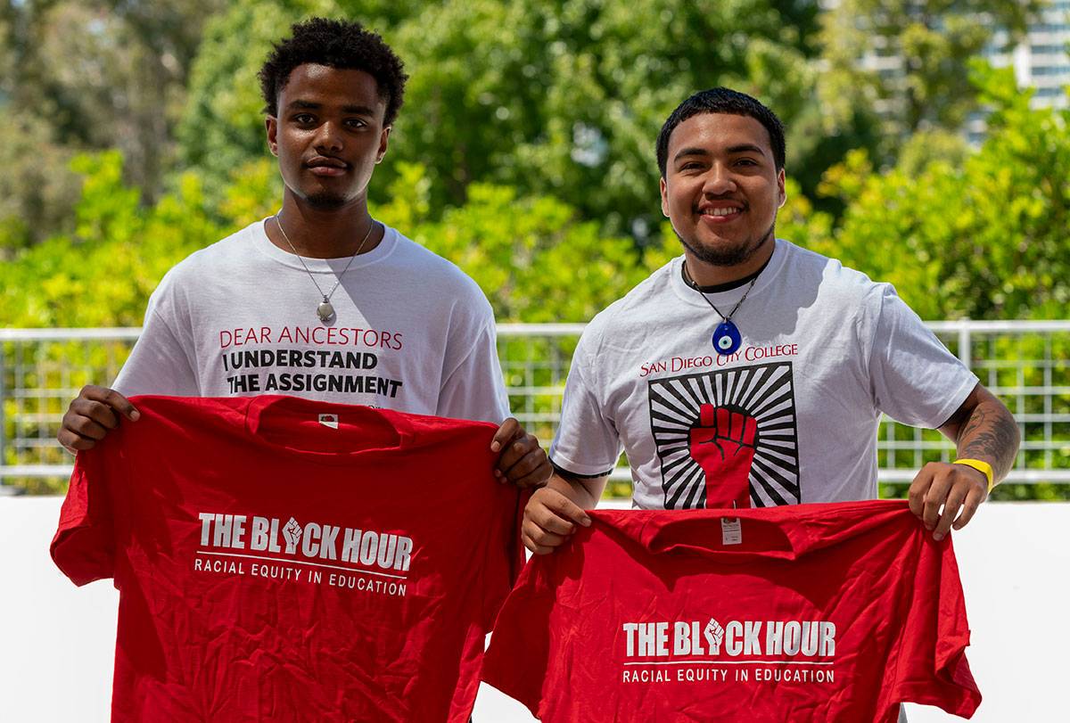 Two students hold up red tee shirts that say The Black Hour