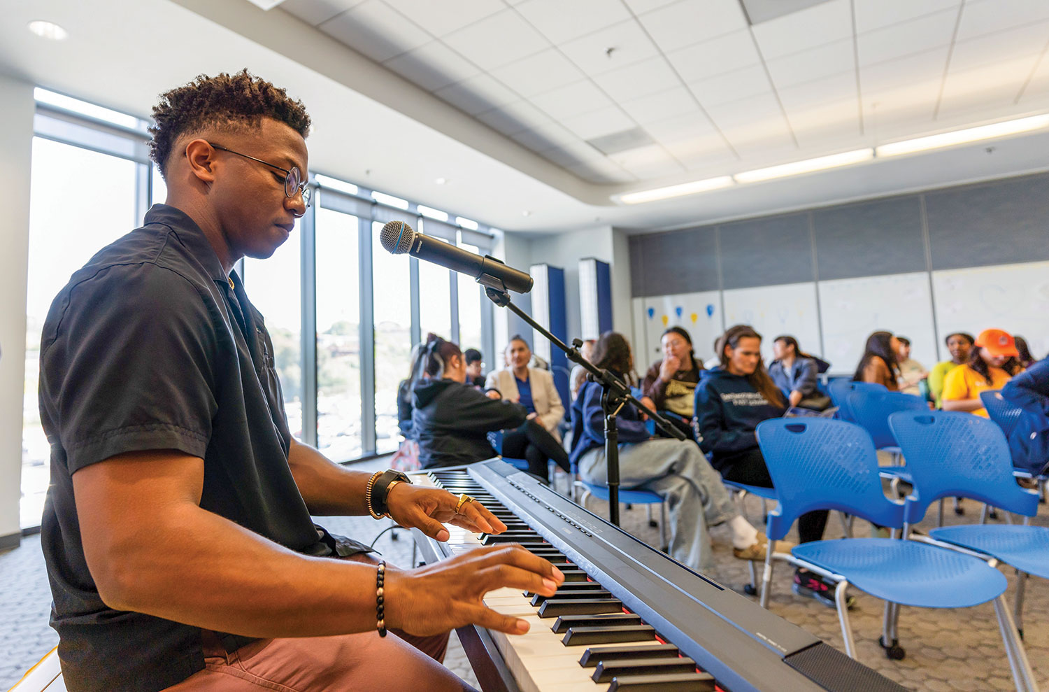 Angel Wilson sitting at a keyboard in a community room.