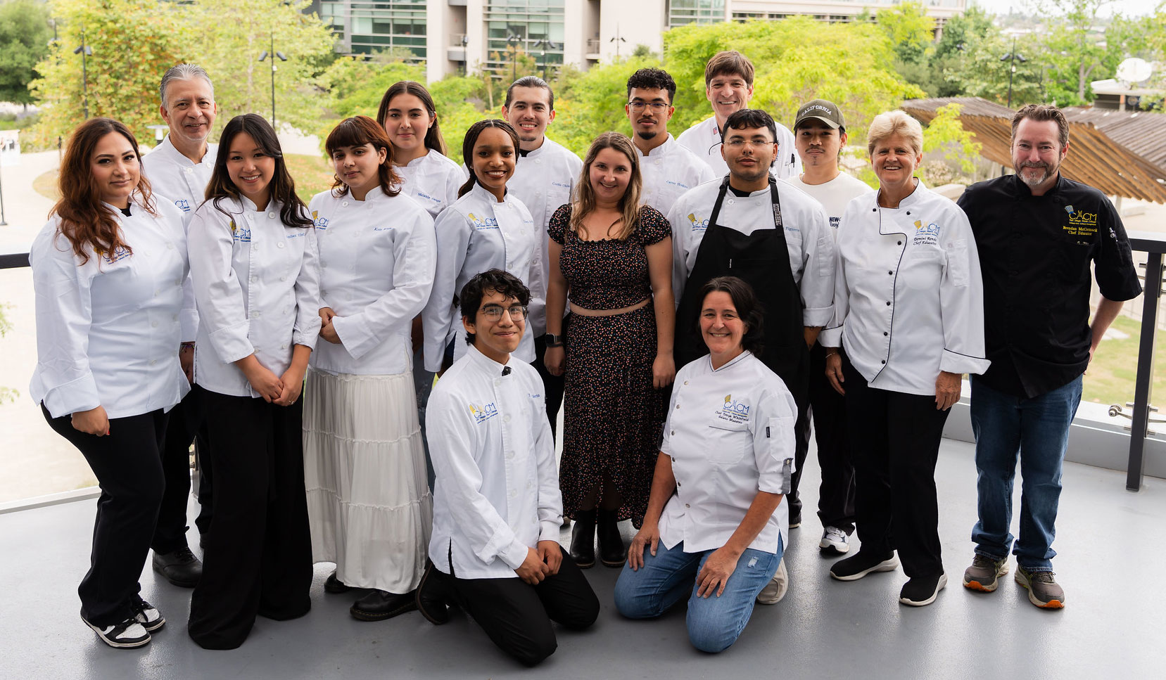 A culinary class with their instructors. All are wearing white cooking jackets and black pants