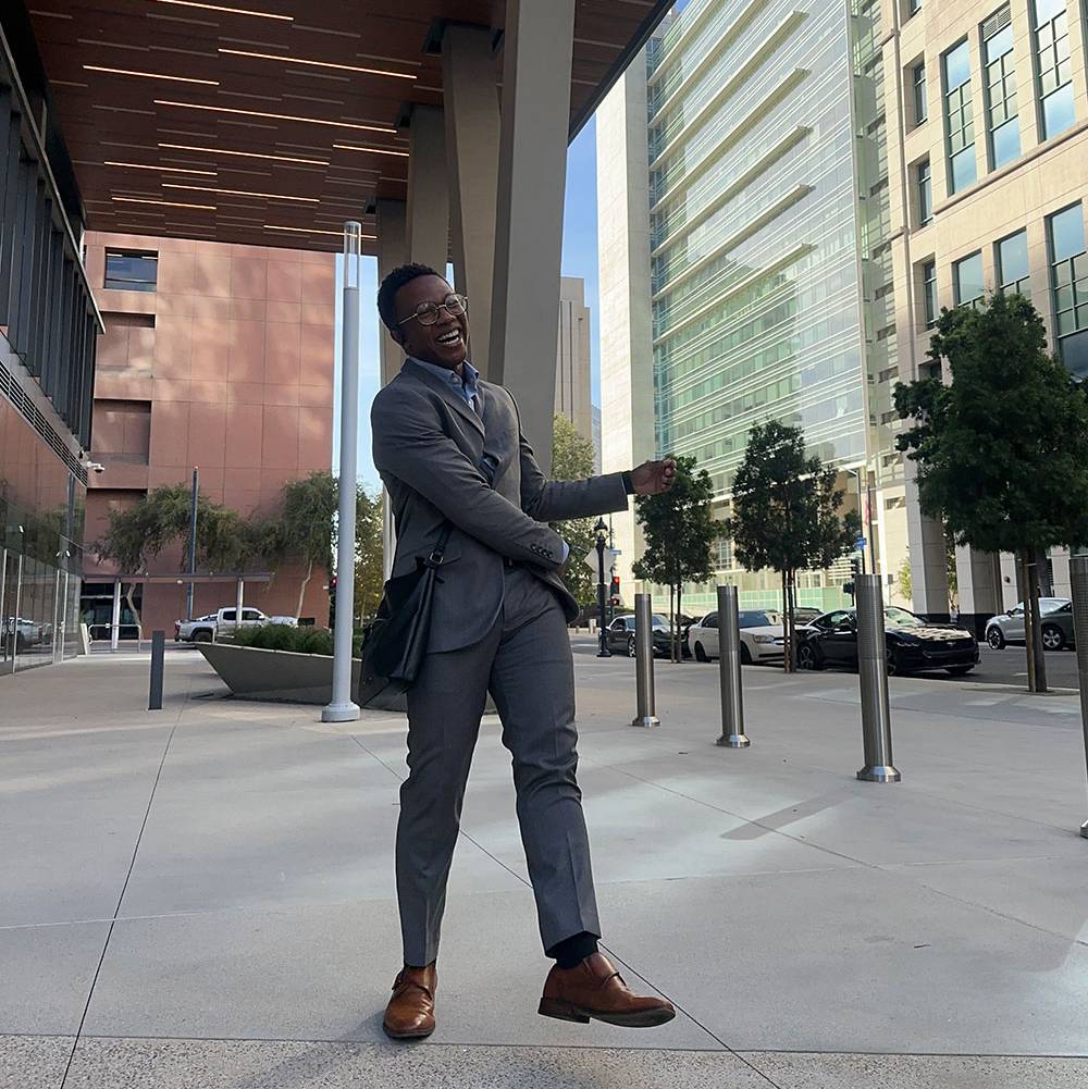 Angel Wilson smiling outside in a gray suit