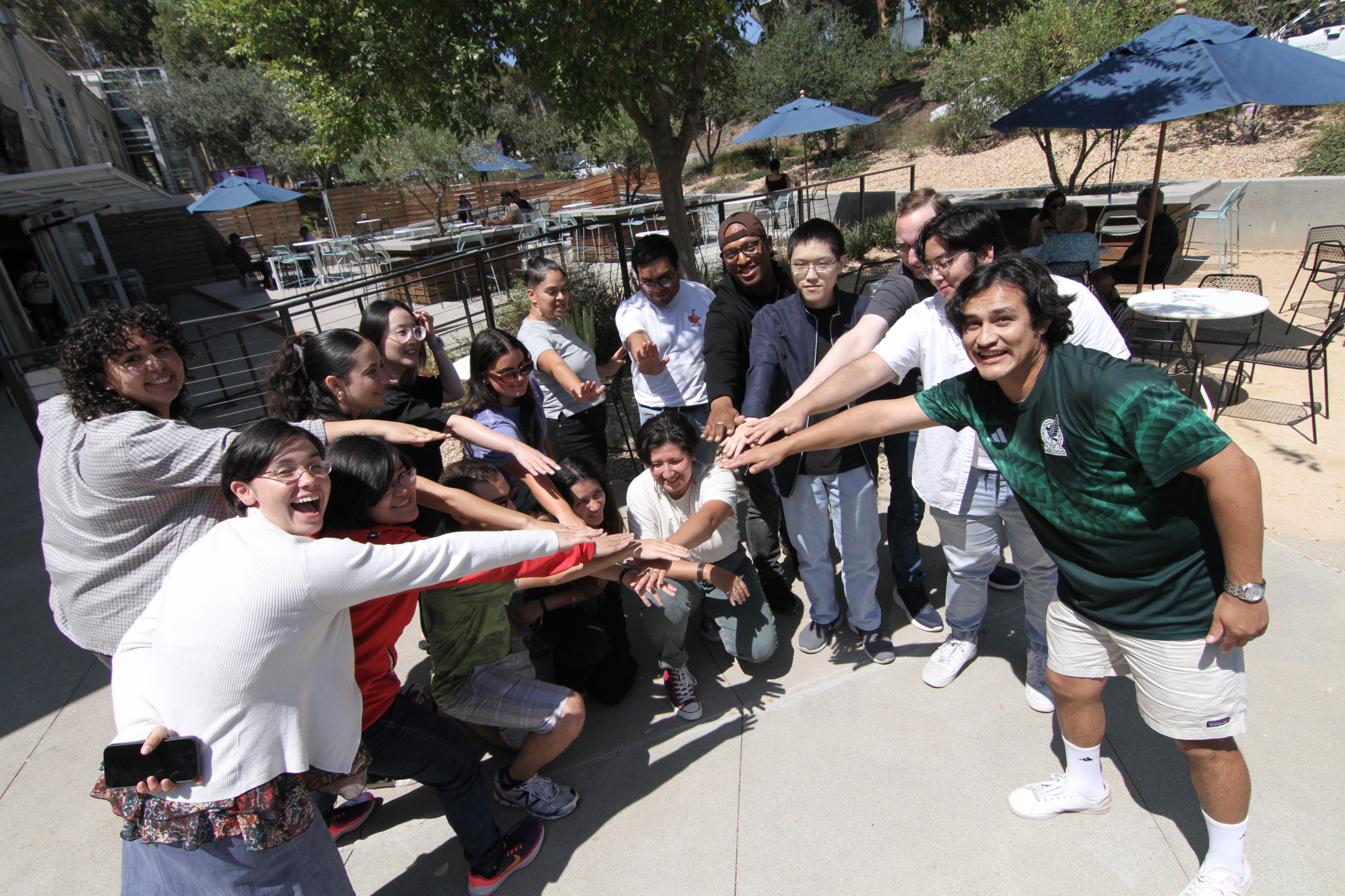 A group of students put their hands together in a circle.