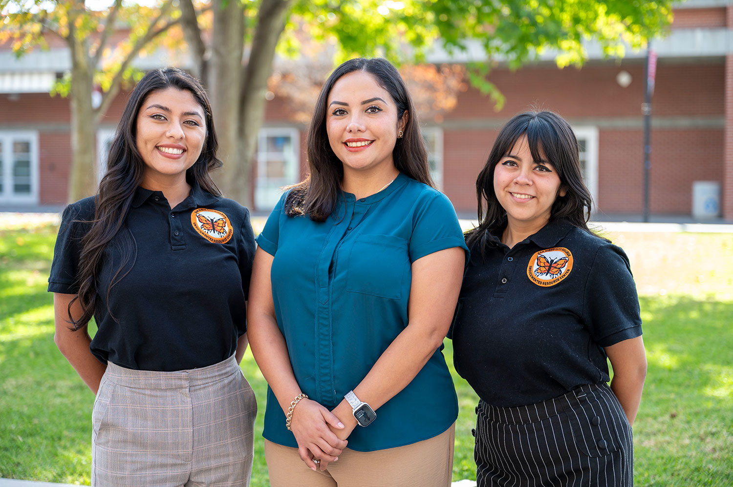 Three women standing outside surrounded by greenery