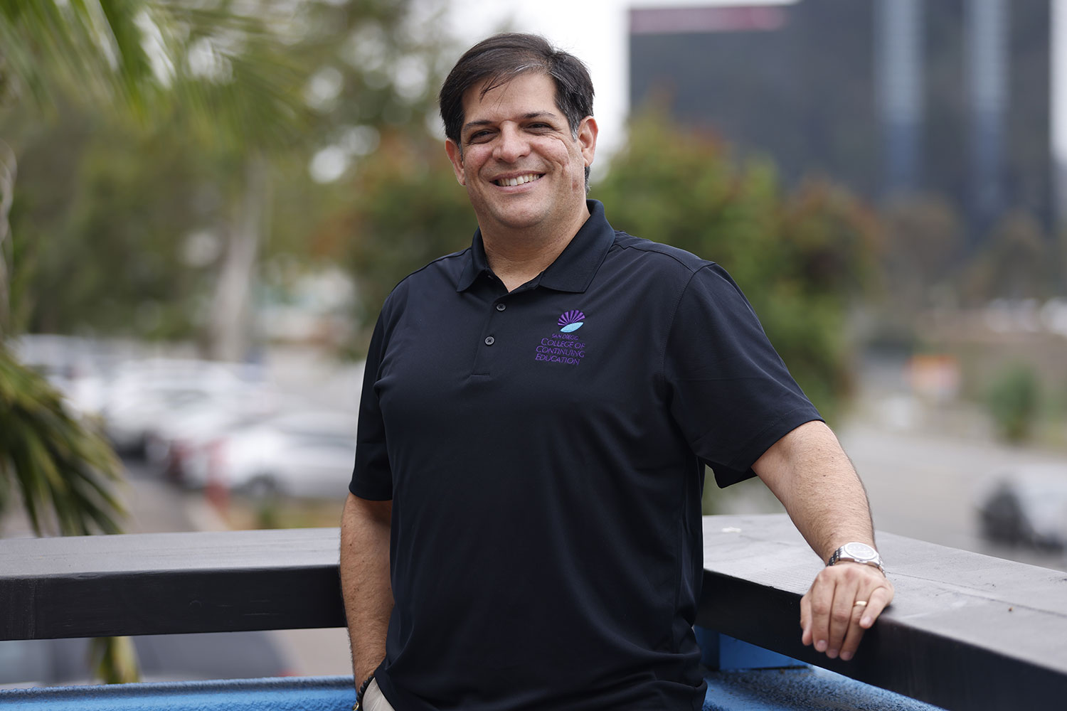 Yahir Meléndez is outside wearing a black polo shirt with the College of Continuing Education logo