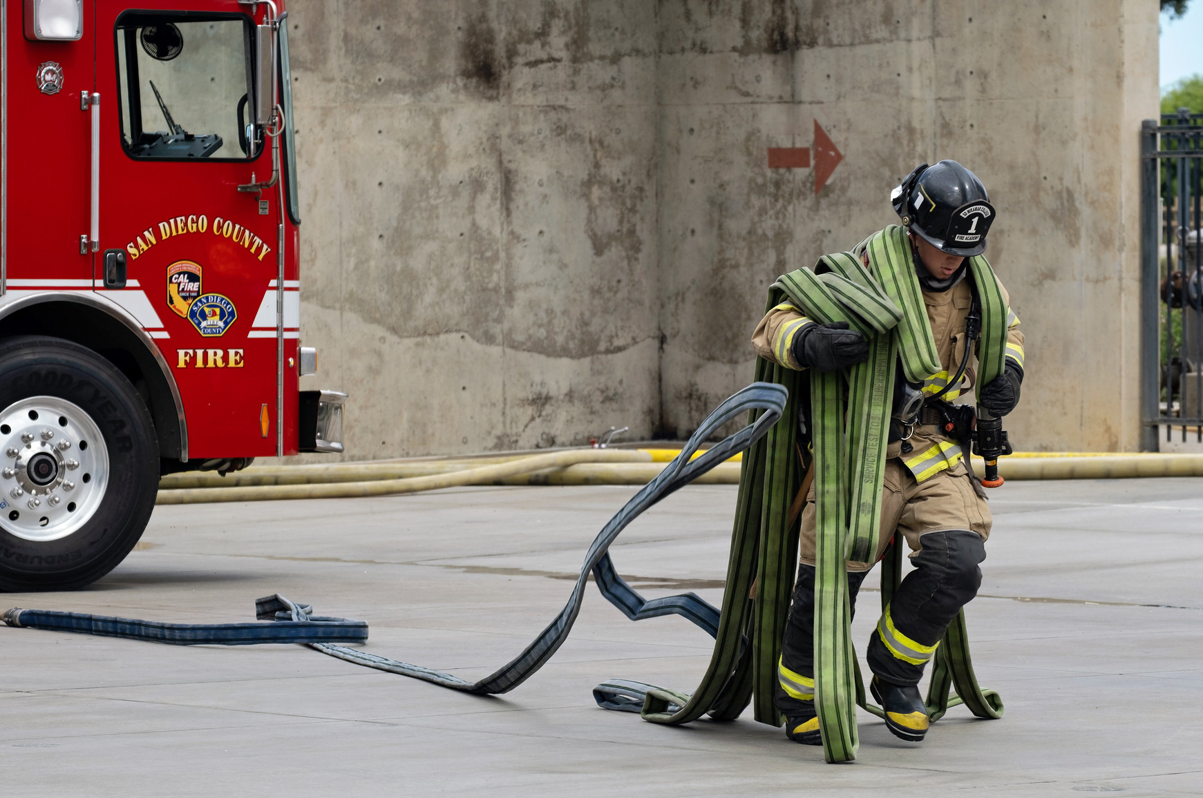 A fire academy student carrying a fire hose on his shoulders.