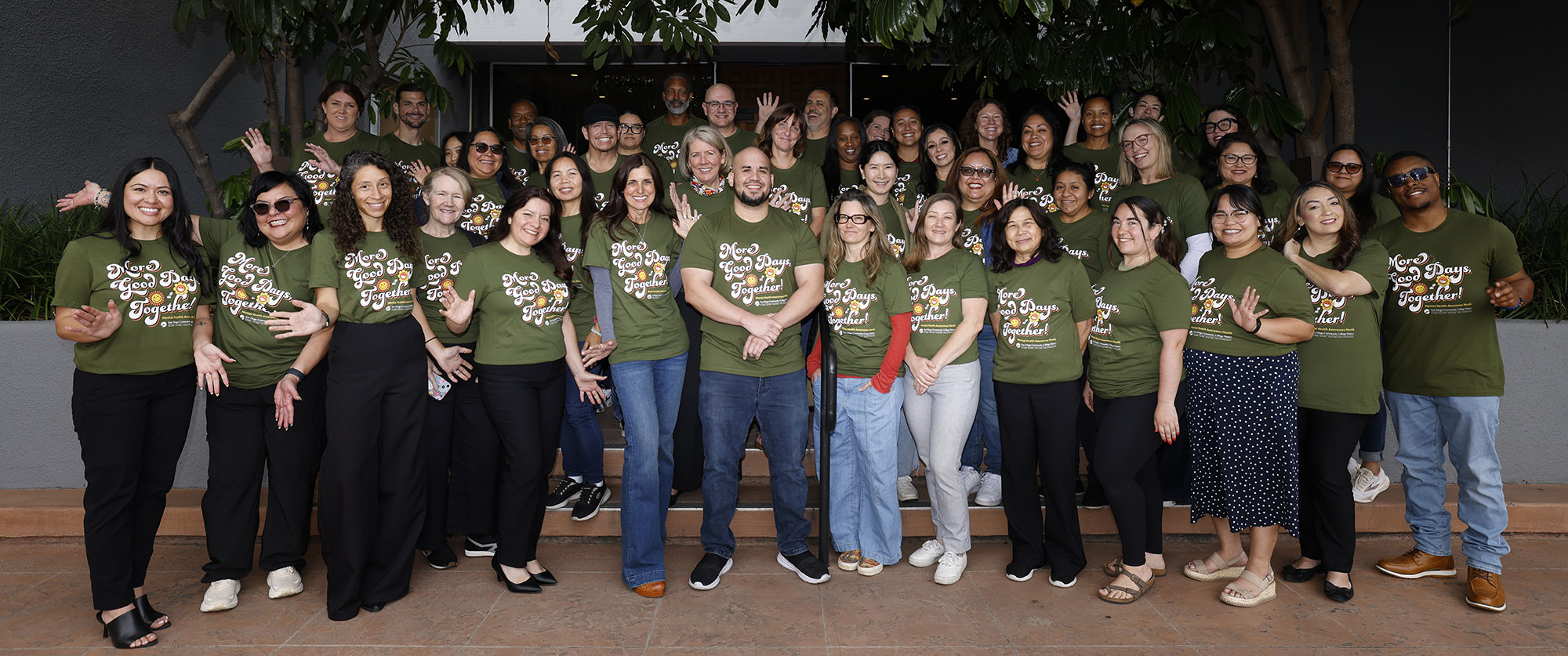 About 30 people gather with matching t-shirts to support Mental Health Awareness. The shirts are olive green and say More Good Days, Together.