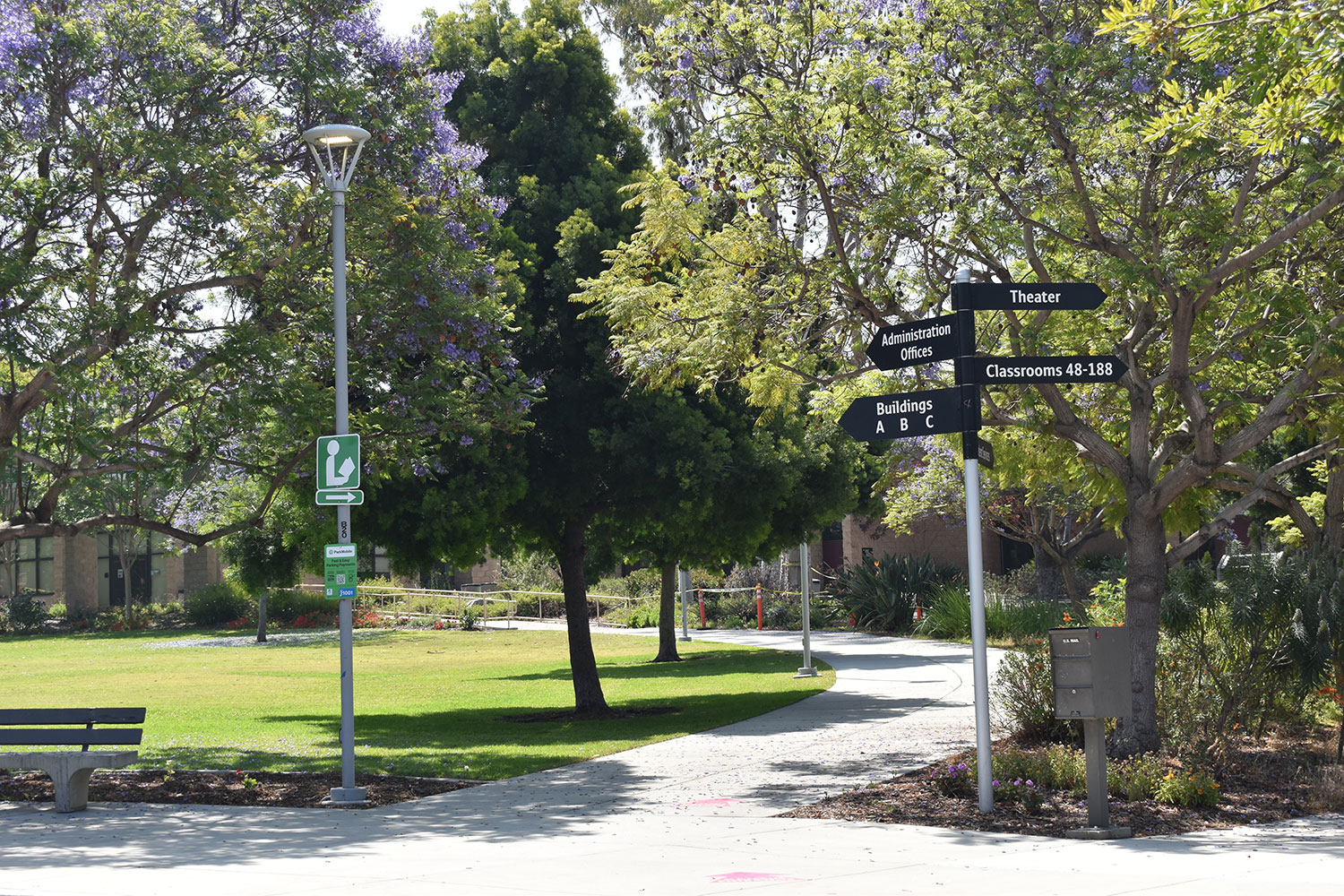 A pole with four arrow signs pointing in different directions to different buildings around campus.