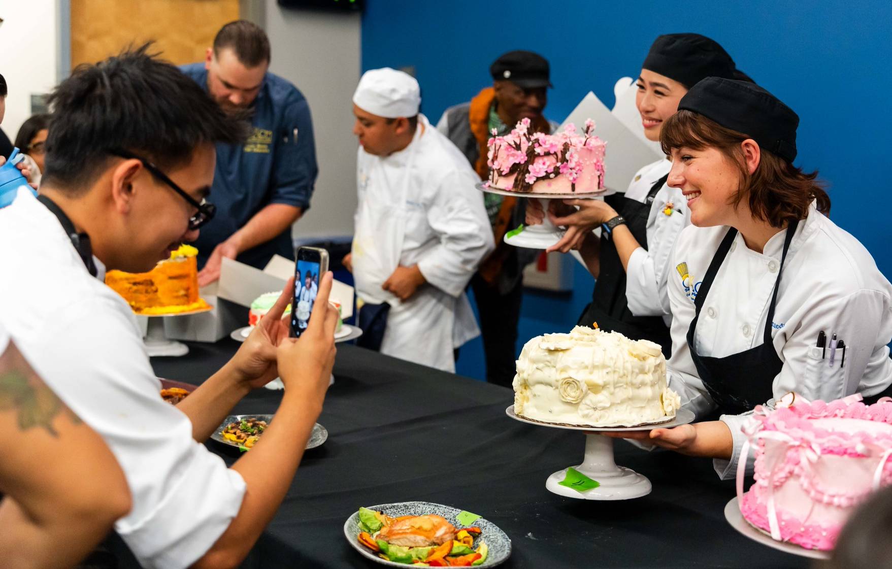 Culinary students hold up the cakes they made for the baking competition