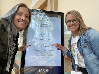 Mesa Online Faculty Mentors Kelly Spoon and Kim Lacher posing by a workshop sign