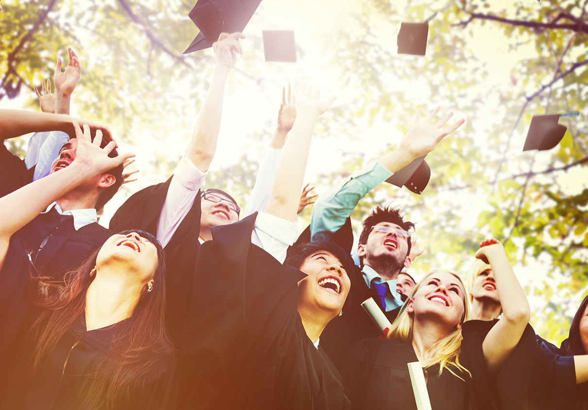 A group of graduates throw their graduation caps in the air