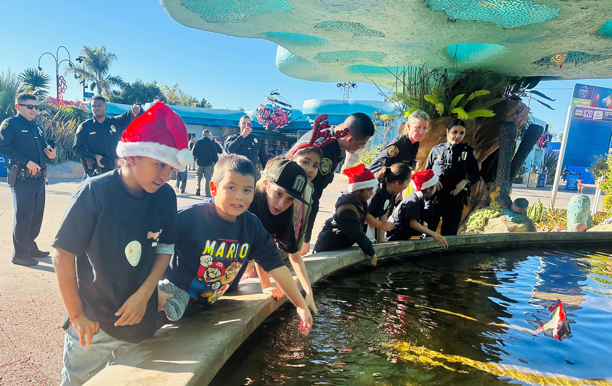 Children and officers put their hands in the water to touch rays at SeaWorld