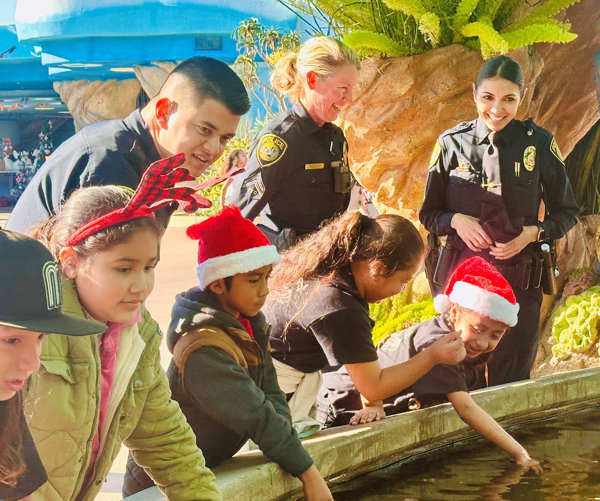 Children and officers put their hands in the water to touch rays at SeaWorld.