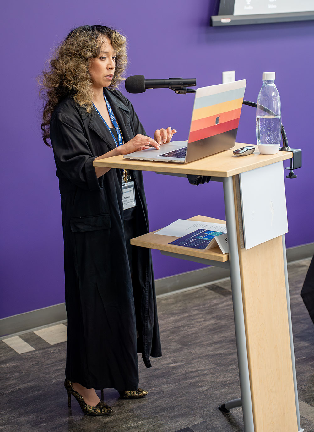 
A lady uses a laptop and speaks at a podium.
