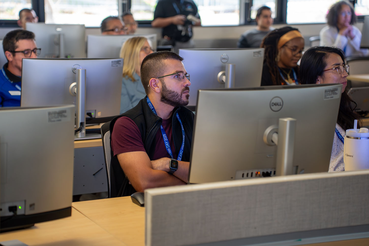 
A classroom full of people sitting at computer stations.
