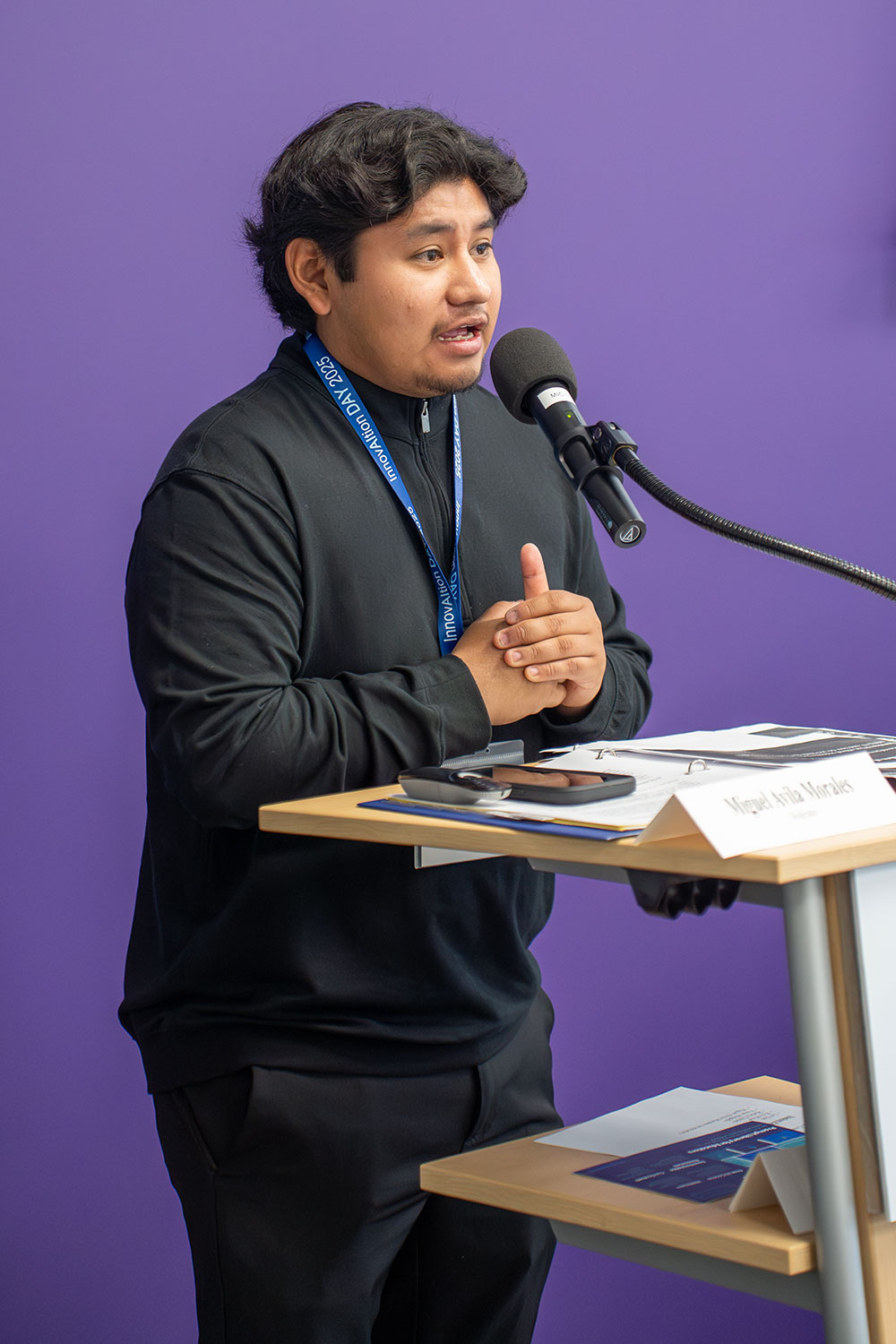 
A student stands at a podium and speaks into a microphone
