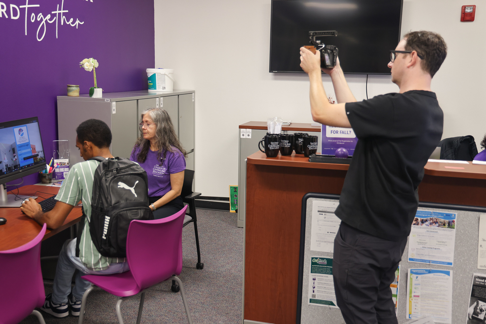 
An employee sits next to a student to help them on a computer.
