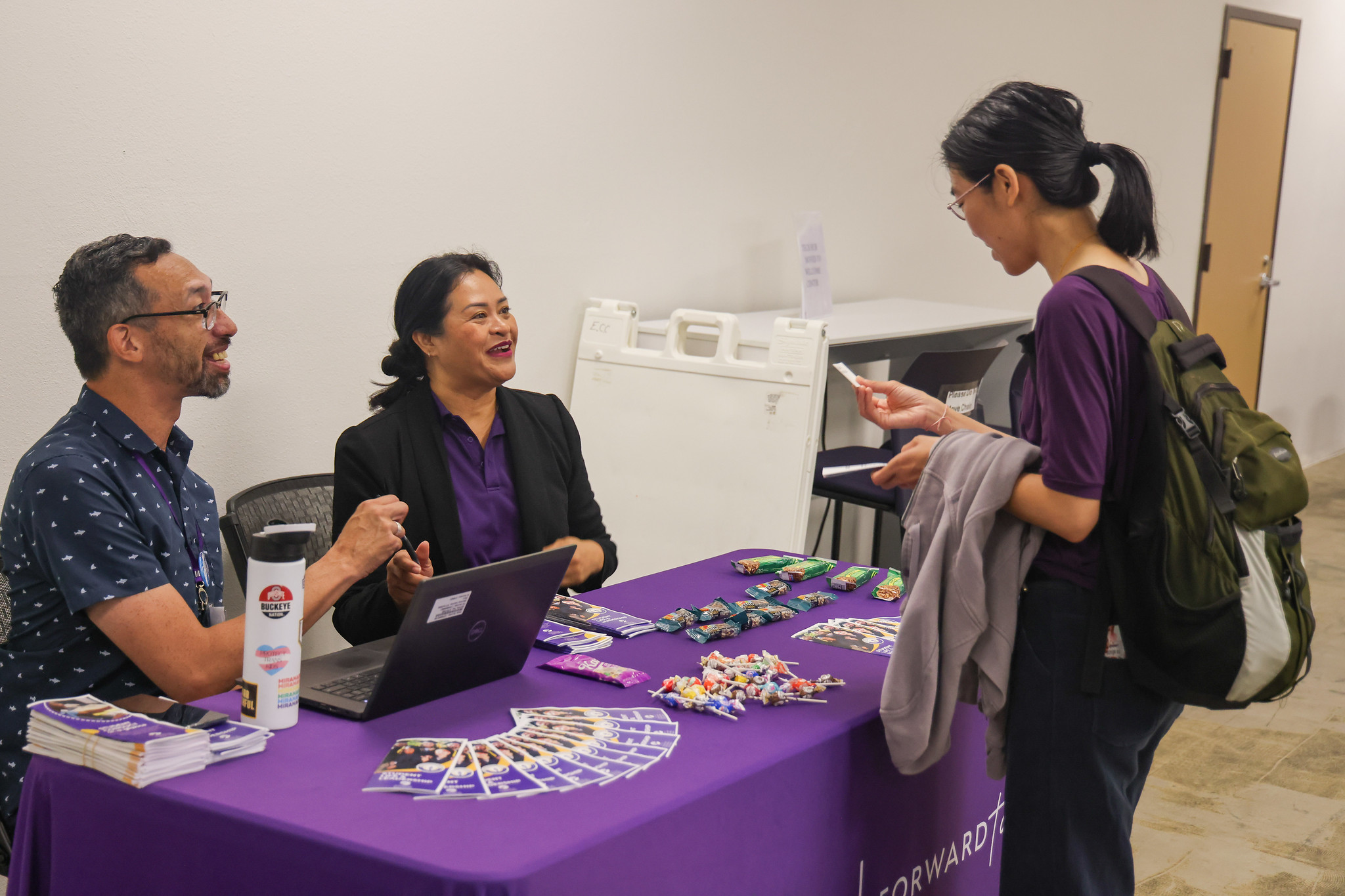 
Two people working at a welcome table helping out a student.
