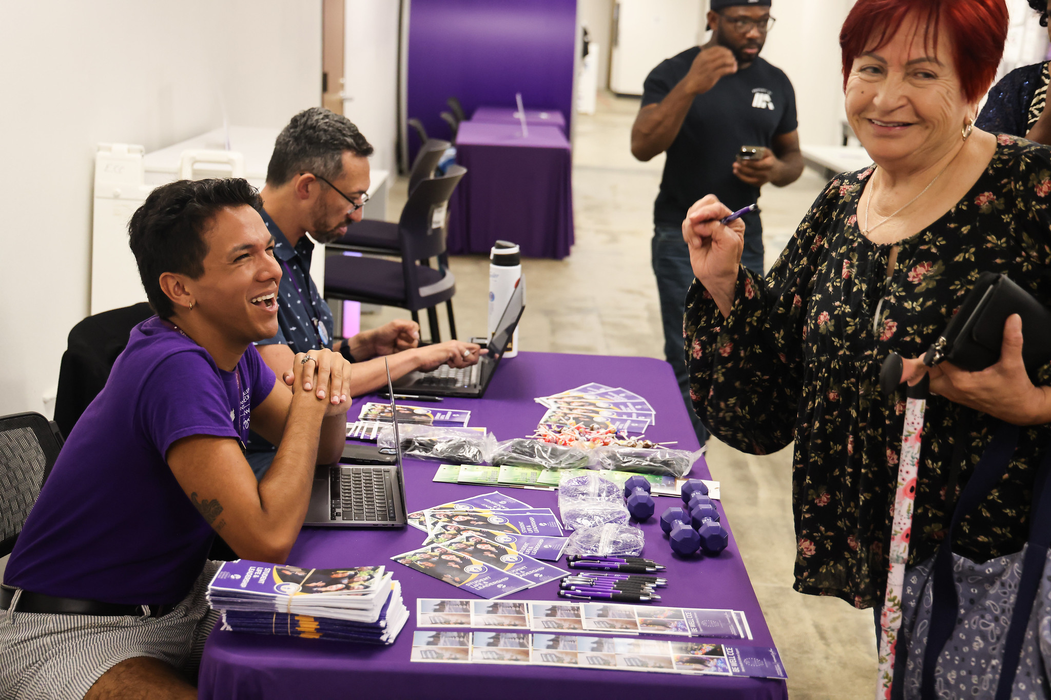 
Two employees sit at a welcome table and engage with students stopping by.
