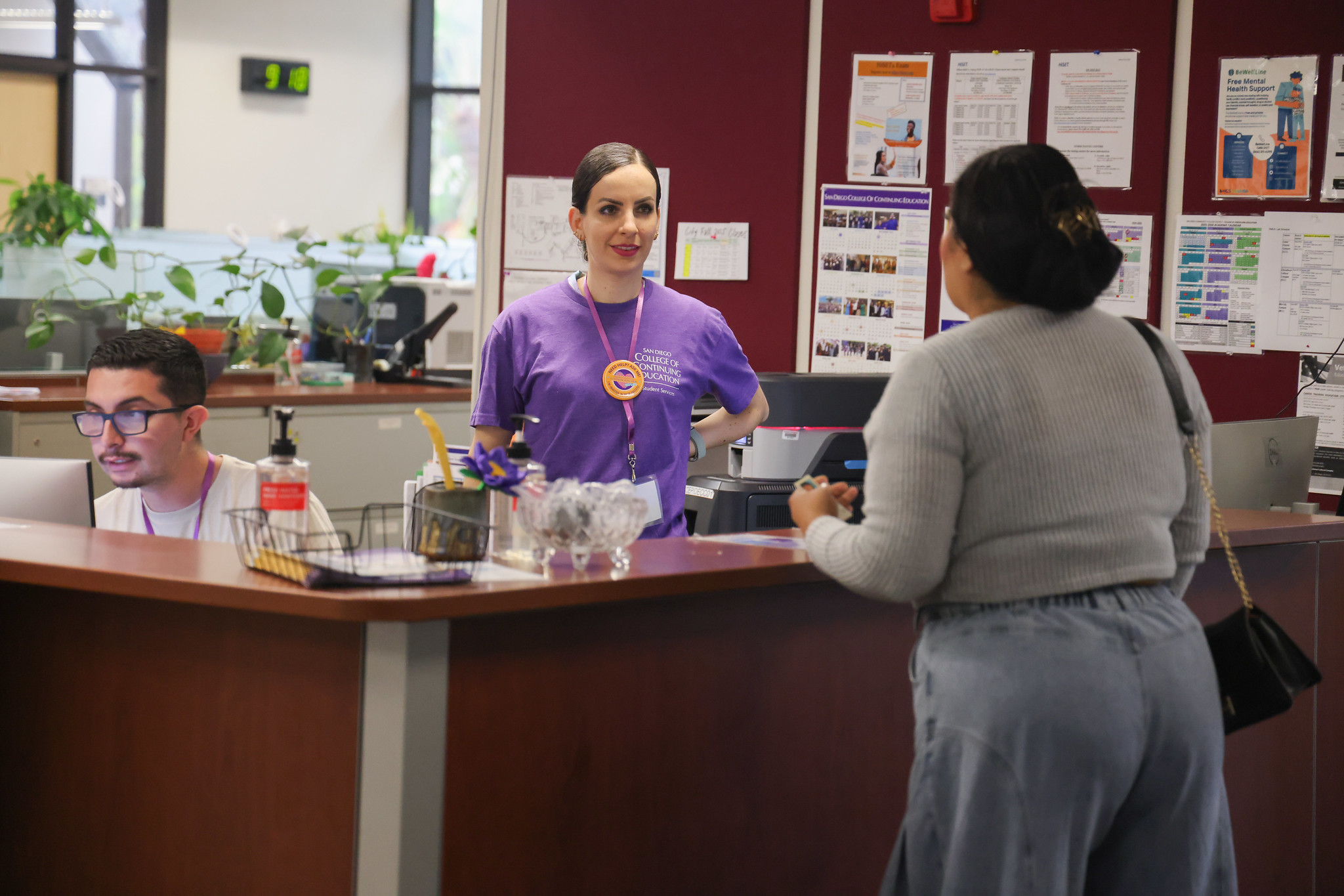 
An employee at a counter helping a student.

