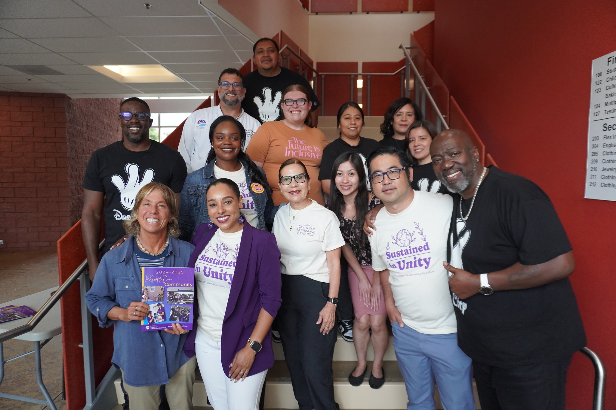 
President Tina King with 13 employees on a staircase on campus.
