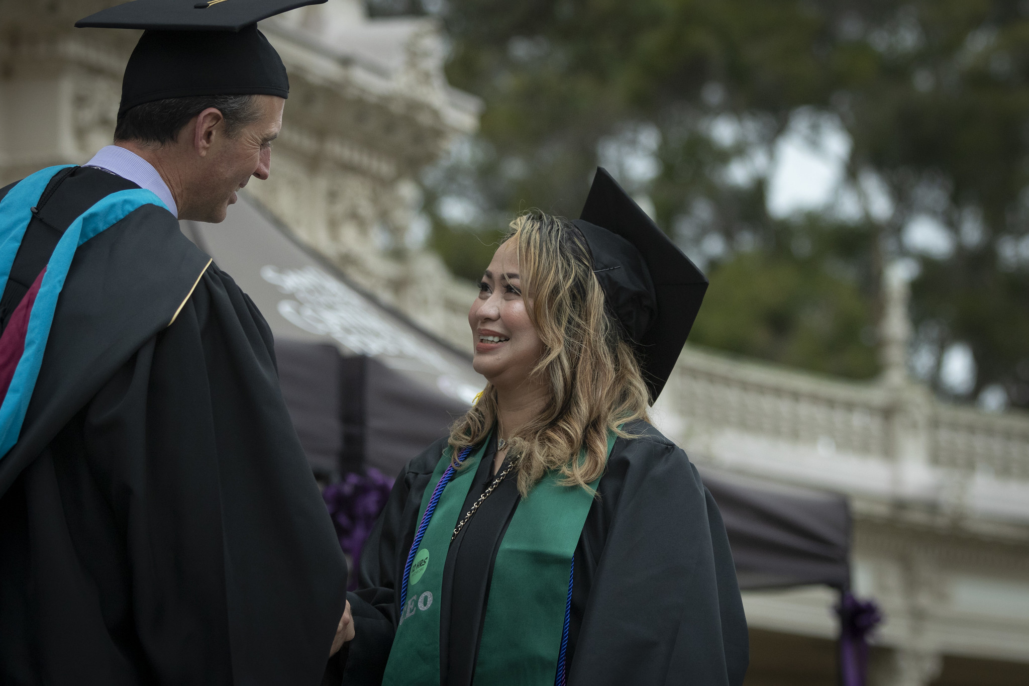 
A graduate on stage shakes hands with Chancellor Gregory Smith.
