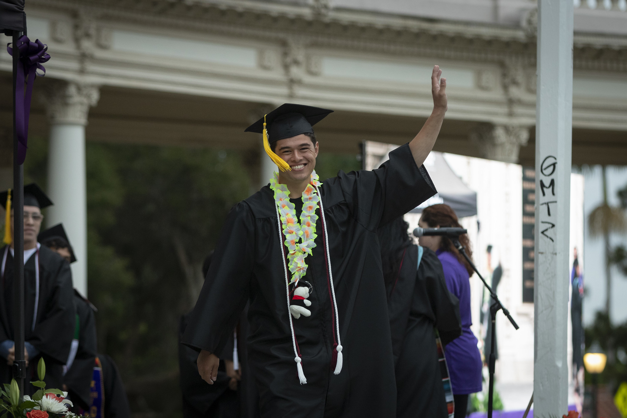 
A graduate on stage waves to the crowd.
